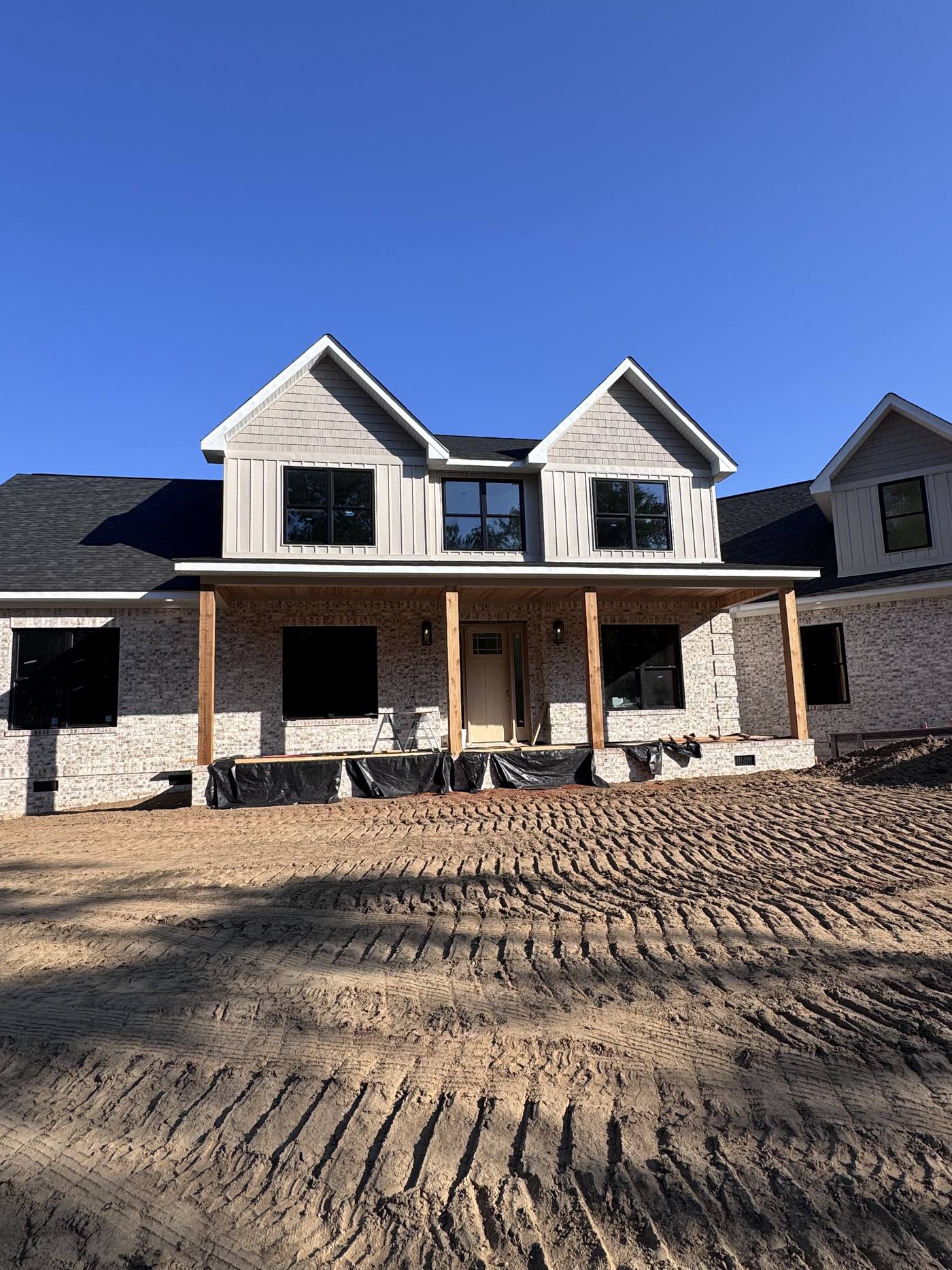 Modern farmhouse under construction with board and batten siding and timber porch posts in the Midlands of South Carolina