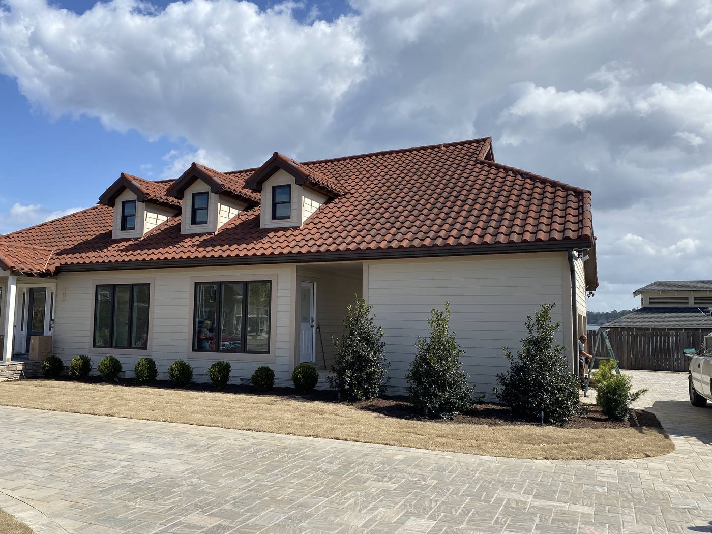 White home with a clay tile roof, dormers and a paver drive in the Midlands of South Carolina