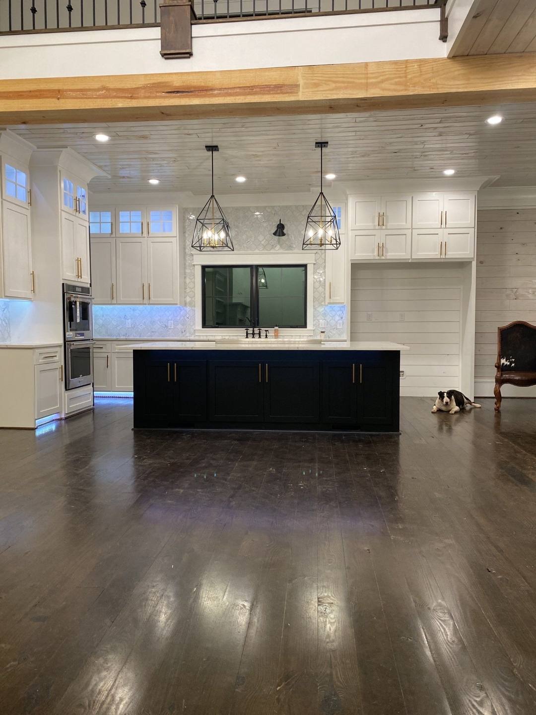 Open-plan kitchen with a dark island, white cabinets and new hardwood flooring in the Midlands of South Carolina