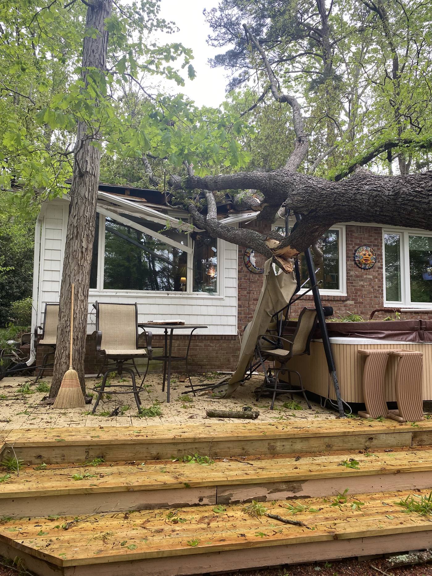 Large tree down across the roof and porch of a home after a storm in the Midlands of South Carolina